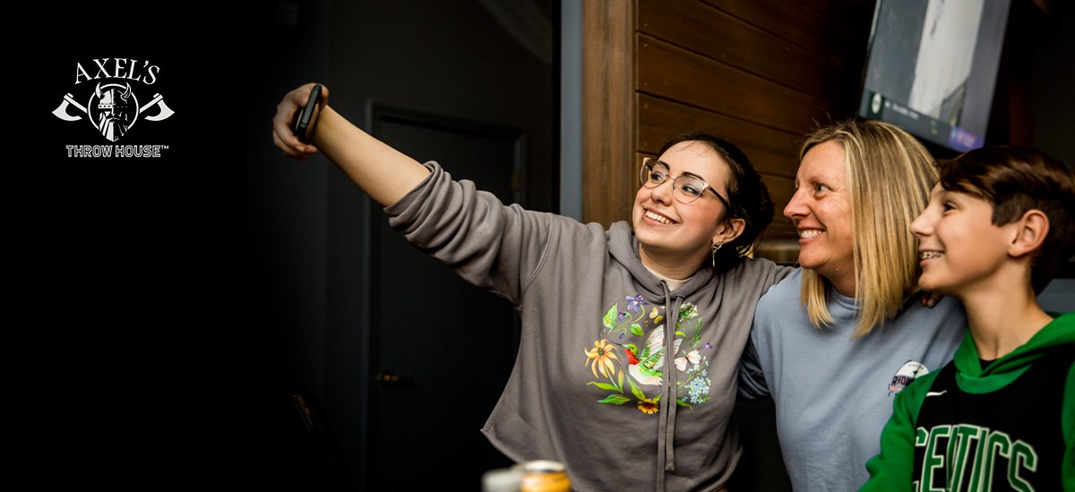 mom and two teens posting for a selfie at Axel's Throw House