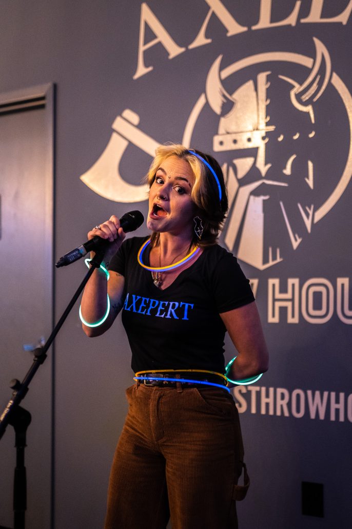 woman singing into a microphone during karaoke night at Axel's Throw House