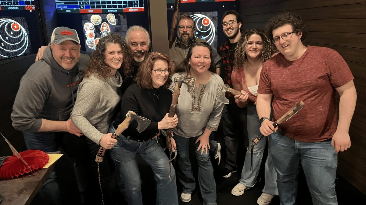 group of nine axe throwers standing in front of digitally projected games and scoreboards at Axel's Throw House