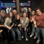group of nine axe throwers standing in front of digitally projected games and scoreboards at Axel's Throw House