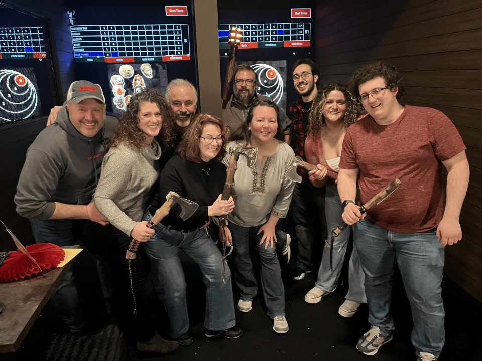 group of nine axe throwers standing in front of digitally projected games and scoreboards at Axel's Throw House